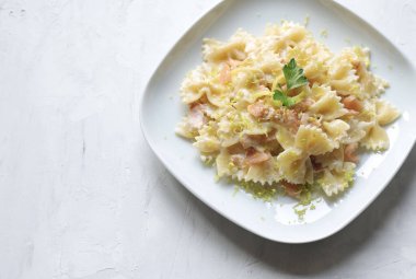 Füme somonlu Farfalle makarna, krema sosu ve beyaz tabakta limon. Genel bakış. İtalyan yemeği kavramı. Boşluğu kopyala.