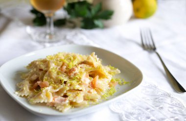 Füme somonlu Farfalle makarna, krema sosu ve beyaz tabakta limon. Genel bakış. İtalyan yemeği kavramı. Boşluğu kopyala.