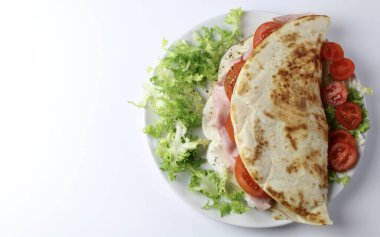 Jambonlu İtalyan piadinası, mozzarella, salata ve domatesler beyaz arka planda izole. Genel bakış. Boşluğu kopyala.