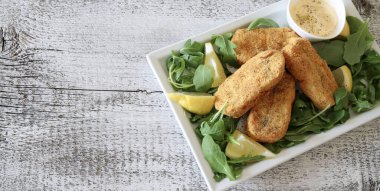 Tahta masada mayonez ve limonla servis edilen çıtır balıklı lezzetli atıştırmalıklar. Genel Görünüm.