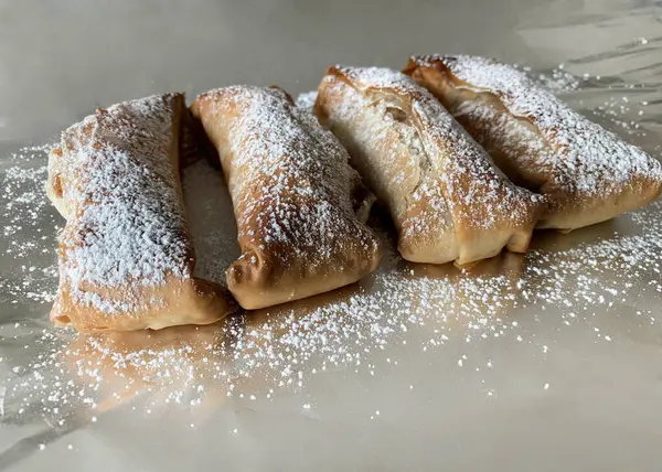 Homemade single portion apple strudel sprinkled with powdered sugar on a gray background. Apfelstrudel. Overhead view.