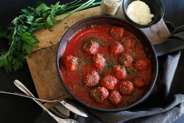 Domates soslu ev yapımı köfteler ve arka planda bir tavada servis edilen baharatlar. Genel Görünüm.