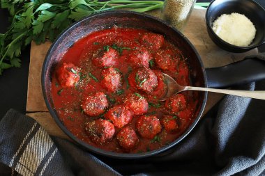 Domates soslu ev yapımı köfteler ve arka planda bir tavada servis edilen baharatlar. Genel Görünüm.