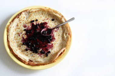 Beyaz arka planda böğürtlen reçeli ile doldurulmuş çeyrekliklere katlanmış ev yapımı krepler. Genel görünüm, boşluğu kopyala.