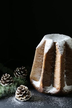 Geleneksel İtalyan Noel pastaları. Pandoro, tipik bir İtalyan tatlısı. Siyah arka planda krema serpiştirilmiş. Noel süsleri. Tatil sezonu.