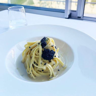 Havyarlı ve tereyağlı Tagliolini beyaz bir tabakta izole edilmiş. İtalyan yemeği. Genel Görünüm.