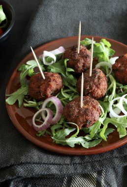 Koyu bir arka planda izole bir tabakta roket yapraklı leziz kızarmış köfteler. Yukarıdan bak. Boşluğu kopyala.