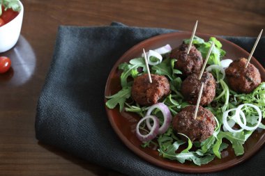 Koyu bir arka planda izole bir tabakta roket yapraklı leziz kızarmış köfteler. Yukarıdan bak. Boşluğu kopyala.