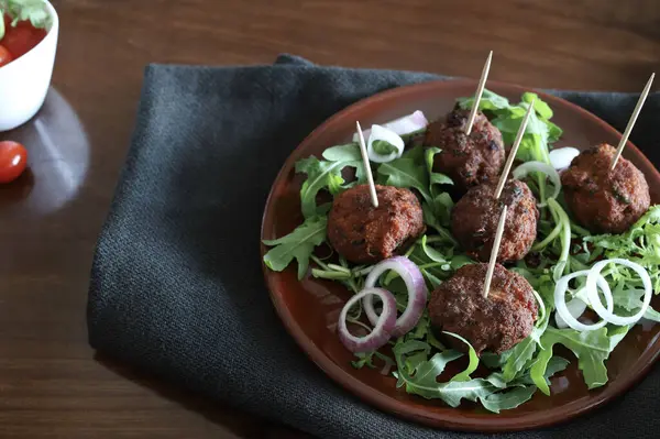 Koyu bir arka planda izole bir tabakta roket yapraklı leziz kızarmış köfteler. Yukarıdan bak. Boşluğu kopyala.
