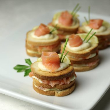 Somon füme ekmeği ve beyaz tabakta krem peynirli kanepe. Lezzetli aperatif. Yakın plan. Genel Görünüm.