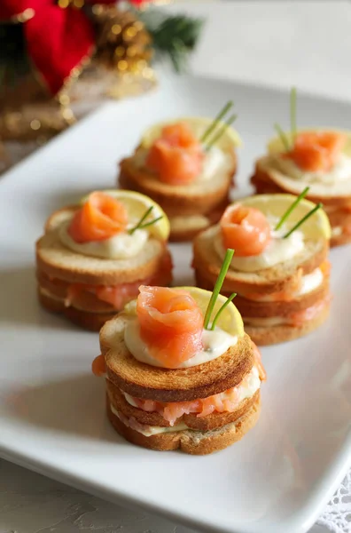Toasted bread with smoked salmon and cream cheese canapes on white plate. Tasty appetizer. Close-up. Overhead view.