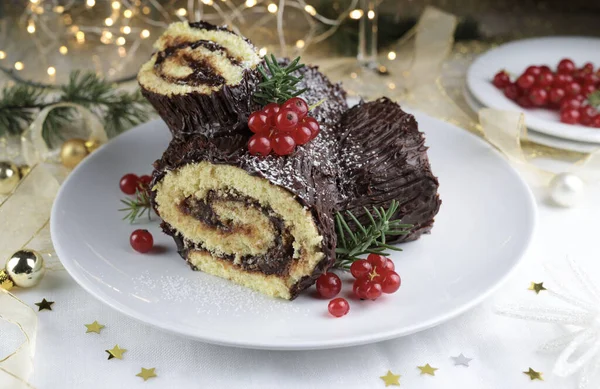 Traditional Christmas dessert. Buche de Noel. Christmas yule log cake with chocolate cream and currant. Holiday season.