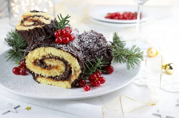 Traditional Christmas dessert. Buche de Noel. Christmas yule log cake with chocolate cream and currant. Holiday season.