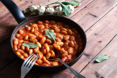 Domates soslu beyaz fasulyeler ve ahşap bir arka planda otlar. Genel bakış. Boşluğu kopyala.