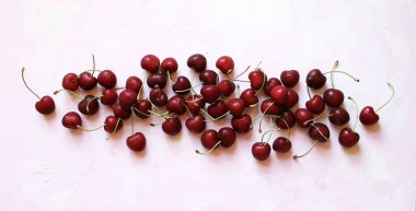 Meyvelerden oluşan yaratıcı bir düzen. Düz yatıyordu. Beyaz arka planda pembe tonlarda izole edilmiş taze kirazlar. Yaz meyvesi. Genel Görünüm.