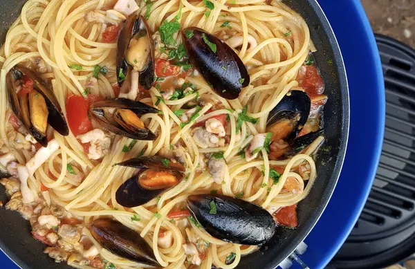 Easy campsite meals, spaghetti with mussels and tomato sauce. Overhead view. Holiday season.