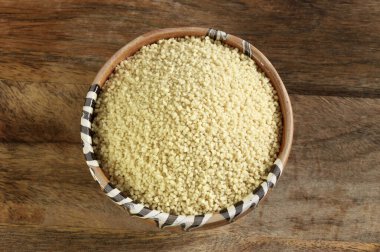 Tahta arka plandaki bir kasede çiğ organik kuskus. Organik yiyecekler. Genel bakış. Boşluğu kopyala.