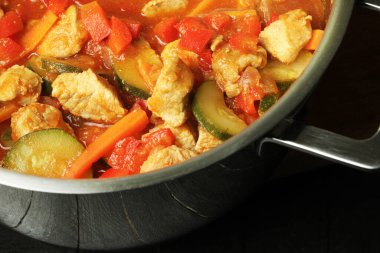 Kabaklı et, havuç, biber, domates ve baharatla pişirilmiş siyah ahşap arka planda. Genel görünüm, yakın çekim, kopyalama alanı.