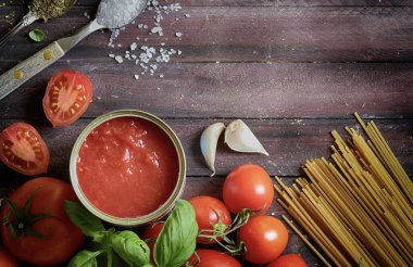 İtalyan yemeği. Ev yapımı domates sosu, fesleğen, buğday ekmeği makarna, sarımsak ve baharat. Domates makarnası pişirmek için gerekli malzemeler. Genel Görünüm.