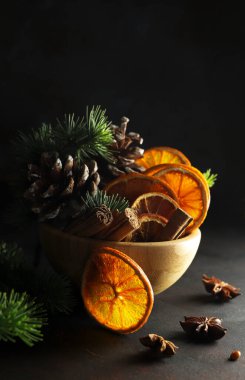 Siyah arka planda kurumuş portakal dilimleri, tarçın ve anason içeren Noel kompozisyonları. Noel ve tatil sezonu.