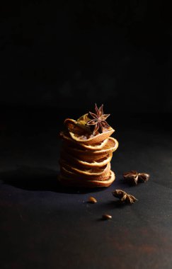 Noel kavramı. Kurumuş portakal dilimleri ve siyah arka planda anason içeren Noel kompozisyonları.