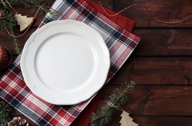 Kırsal ahşap arka planda boş beyaz tabak ile Noel yemeği sınırı. Noel ve tatil sezonu. Genel bakış. Boşluğu kopyala.