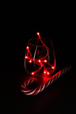 İçinde kırmızı ışıklar olan cam, koyu arka planda izole edilmiş. Noel ve tatil sezonu.