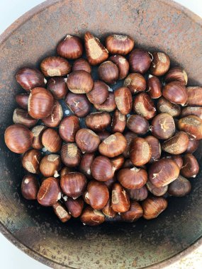 Demir tavada pişmiş kestaneler. Kızarmış kestane. Sonbahar meyvesi. Sonbaharda açık hava yemekleri..