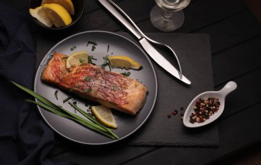 Izgara ya da kızarmış somon, otlar, sarımsak, baharatlar ve koyu arkaplanda limon. Sağlıklı gıda konsepti. Genel Görünüm.