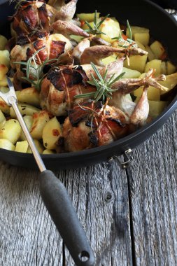 Ahşap zemin üzerinde patates ve otlarla pişirilmiş bıldırcın. Uzayı kopyala Genel Görünüm.