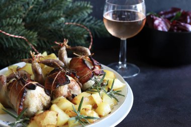 Arka planda patates ve otla pişirilmiş bıldırcın. Noel ve tatil sezonu. Boşluğu kopyala.