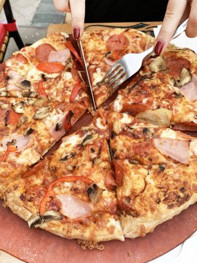 Tahta kesme tahtasının üzerinde çeşitli malzemelerle dilimlenmiş lezzetli bir pizza. İtalyan yemeği. Genel Görünüm.