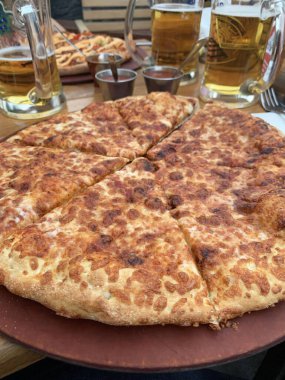 Tahta kesme tahtasının üzerinde çeşitli malzemelerle dilimlenmiş lezzetli bir pizza. İtalyan yemeği. Genel Görünüm.