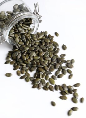 Beyaz arka planda kabuksuz doğal yeşil balkabağı tohumları. Sağlıklı gıda konsepti. Genel bakış. Boşluğu kopyala.