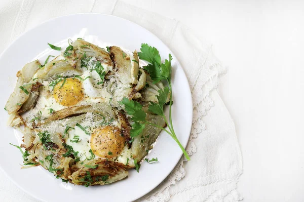 Homemade fried eggs and fennel with herb in an iron pan on white background. Healthy and vegetarian food. Overhead view.