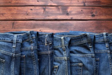 Ahşap arka planda izole edilmiş mavi kot yığını. Moda kıyafet konsepti. Genel bakış. Boşluğu kopyala.