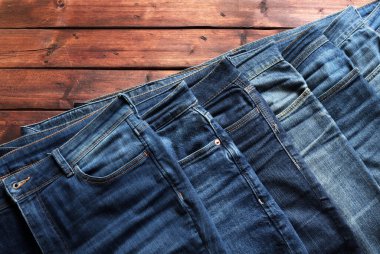 Ahşap arka planda izole edilmiş mavi kot yığını. Moda kıyafet konsepti. Genel bakış. Boşluğu kopyala.