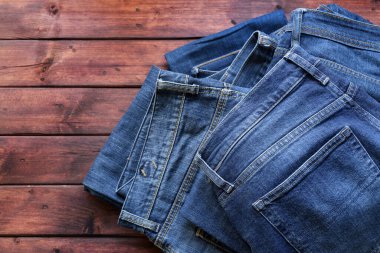 Ahşap arka planda izole edilmiş mavi kot yığını. Moda kıyafet konsepti. Genel bakış. Boşluğu kopyala.