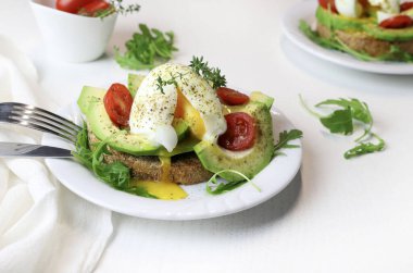 Beyaz arka planda haşlanmış yumurta ve domatesli avokado tostu. Sağlıklı gıda konsepti. Genel Görünüm.