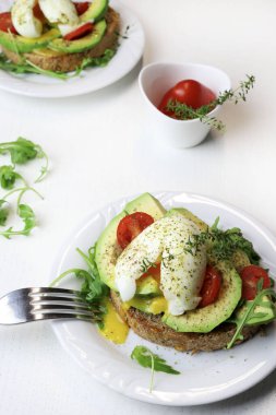 Beyaz arka planda haşlanmış yumurta ve domatesli avokado tostu. Sağlıklı gıda konsepti. Genel Görünüm.