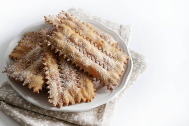 Karnaval sezonu. Ev yapımı geleneksel İtalyan karnaval tatlıları: Beyaz arka planda krema şekeri serpiştirilmiş chiacchiere. Uzayı kopyala Genel Görünüm.