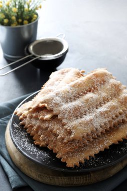 Karnaval sezonu. Ev yapımı geleneksel İtalyan karnaval tatlıları: Koyu arkaplanda krema şekeri serpiştirilmiş chiacchiere. Boşluğu kopyala. 