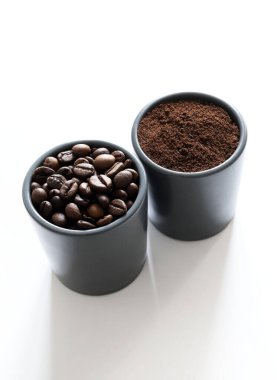İki gri kahve fincanı, kahve çekirdeği ve beyaz arka planda izole edilmiş öğütülmüş kahve. Genel bakış. Boşluğu kopyala.