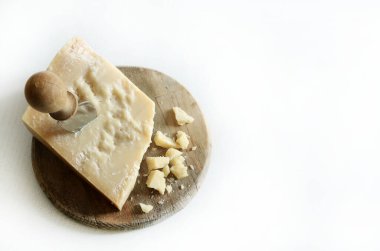 Beyaz arka planda izole edilmiş ahşap bir kesme tahtasının üzerinde İtalyan parmesan ya da parmigiano reggiano peyniri. Boşluğu kopyala.