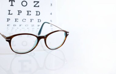 Gözlük ve göz çizelgesi beyaz arka planda izole edilmiş. Moda ve göz sağlığı. Boşluğu kopyala.