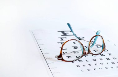 Gözlük ve göz çizelgesi beyaz arka planda izole edilmiş. Moda ve göz sağlığı. Boşluğu kopyala.