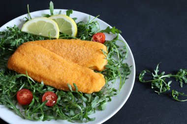 Siyah arka planda salata ve limonlu kızarmış balık filetosu. Genel bakış. Boşluğu kopyala.