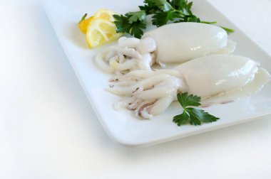 Beyaz arka planda limonlu ve otlu taze mürekkep balığı. Deniz ürünleri. Tam üstte.