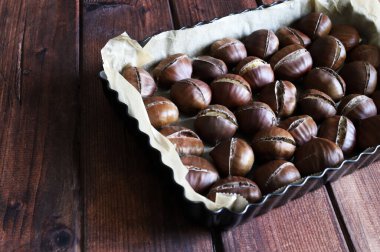 Ahşap bir arka planda fırında kestane. Sonbahar yemeği. Tam üstte.