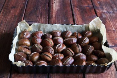 Ahşap bir arka planda fırında kestane. Sonbahar yemeği. Tam üstte.